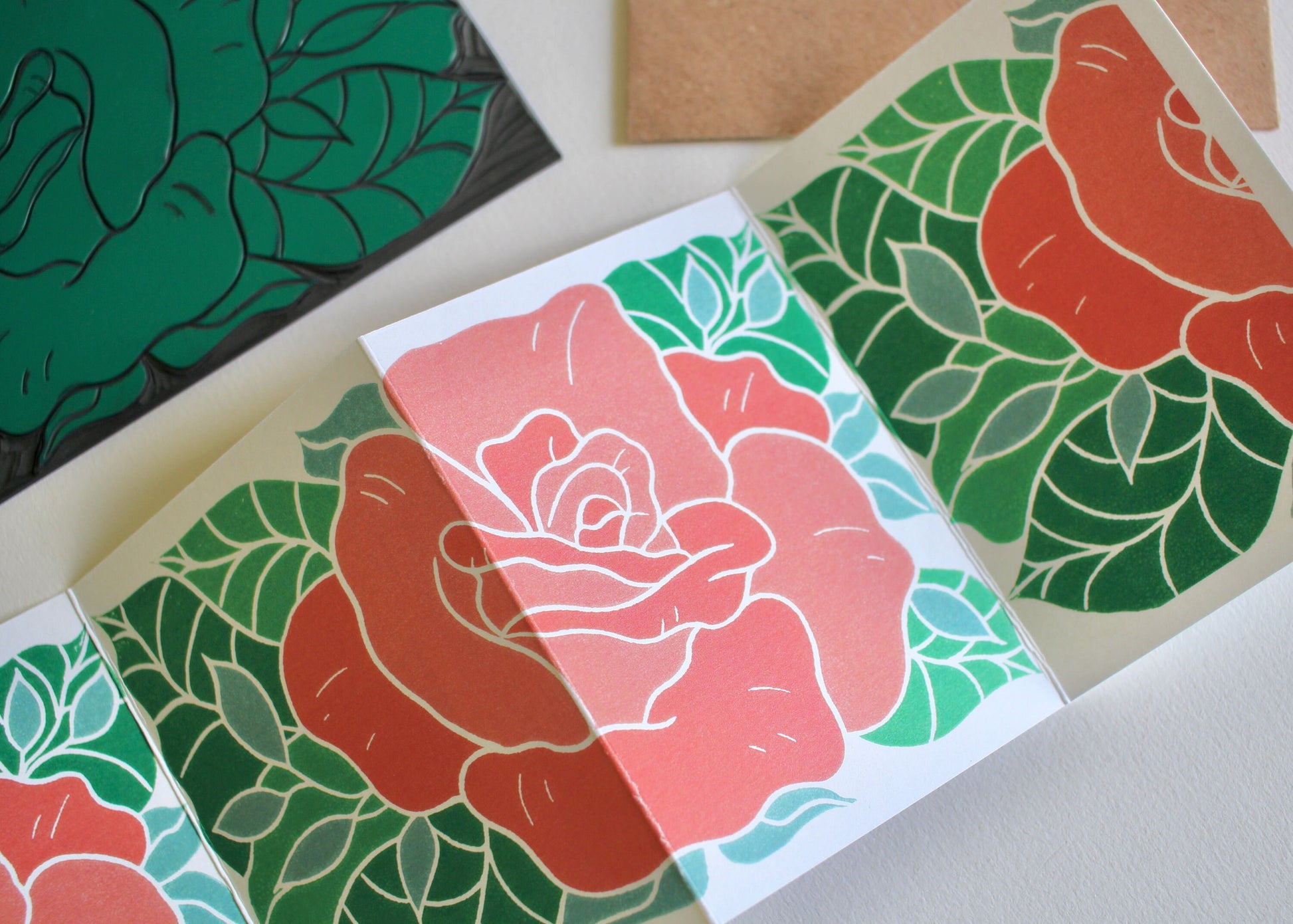 A folded concertina art card featuring a linocut rose and leaves artwork printed on both sides