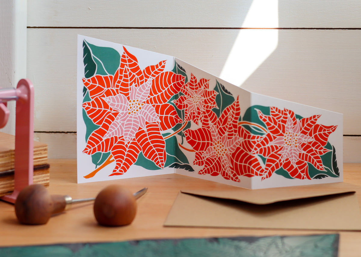Botanical poinsettia Christmas card styled with linocut carving gouges in a Norfolk garden studio
