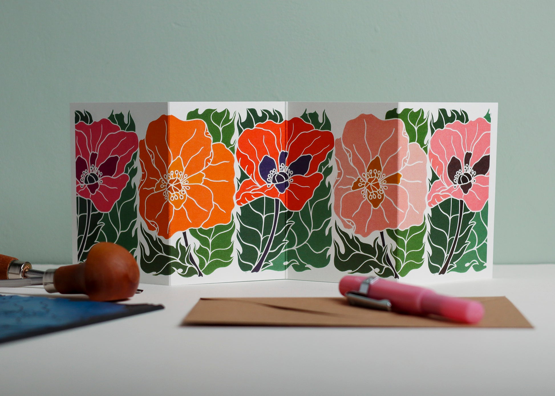 Poppy Parade botanical Garland card shown fully extended (105 x 297mm), displaying complete hand-carved linocut design. Modern cottagecore poppies, perfect for mantlepiece display.