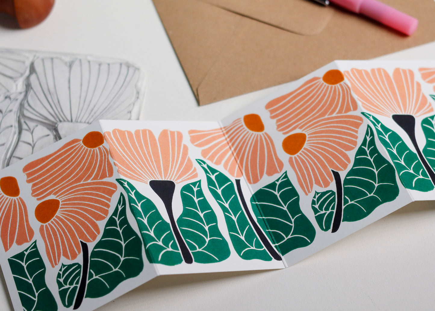 Garden Chorus botanical Garland card shown fully extended (105 x 297mm), displaying complete hand-carved linocut design. Modern cottagecore flowers portrait in peach and green, perfect for mantlepiece display.