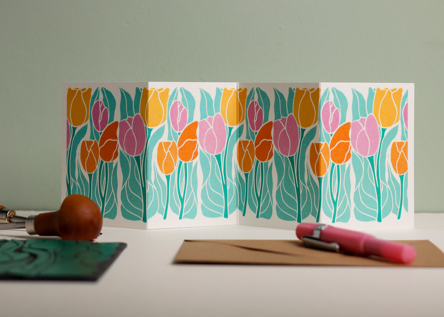 Spring Tulips Garland card featuring hand-carved linocut botanical portrait in a colourful pink, yellow and orange palette. Double-sided concertina greeting card with bold, contemporary cottagecore design on eco-friendly recycled cardstock.