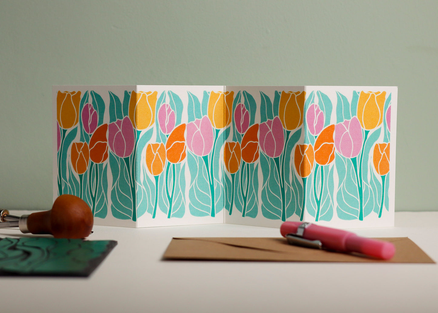 Springtime tulip botanical Garland card shown fully extended (105 x 297mm), displaying complete hand-carved linocut design. Modern cottagecore tulip portrait in colourful yellows, oranges and pinks, perfect for mantlepiece display
