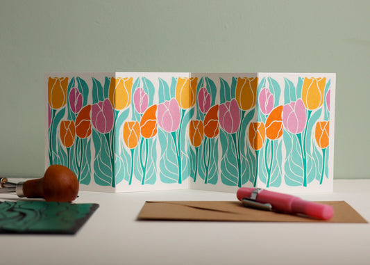 Springtime tulip botanical Garland card shown fully extended (105 x 297mm), displaying complete hand-carved linocut design. Modern cottagecore tulip portrait in colourful yellows, oranges and pinks, perfect for mantlepiece display