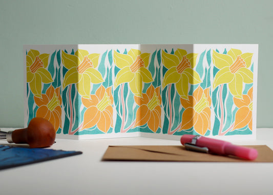 Welsh Daffodil botanical Garland card shown fully extended (105 x 297mm), displaying complete hand-carved linocut design. Modern cottagecore daffodil portrait in yellow and orange, perfect for mantlepiece display.