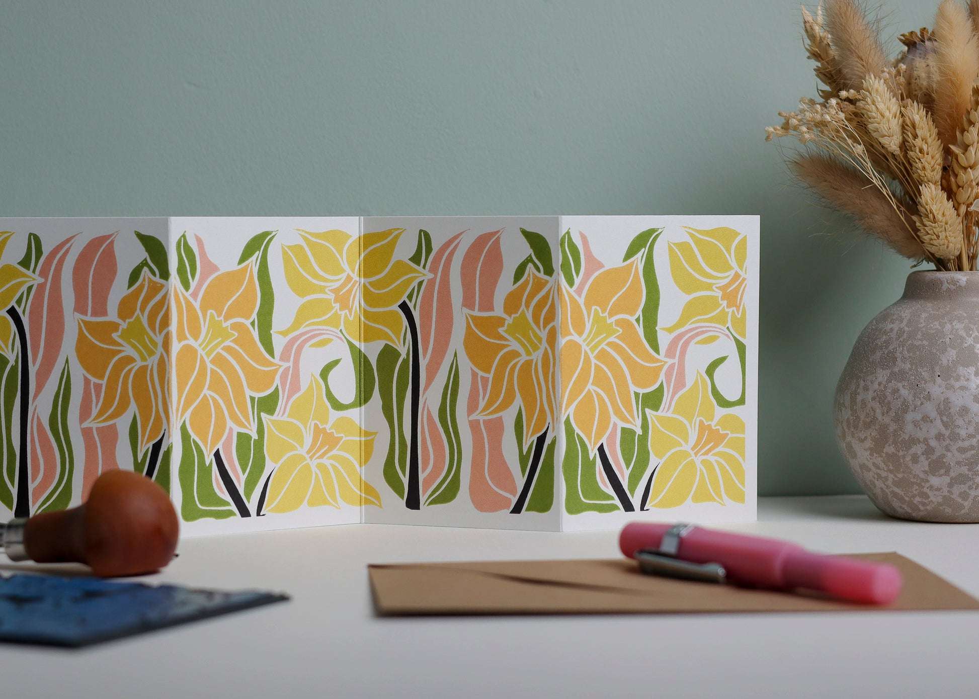 Daffodil Garland card featuring hand-carved linocut botanical portrait in yellow, green and pink. Double-sided concertina greeting card with bold, contemporary cottagecore design on eco-friendly recycled cardstock.
