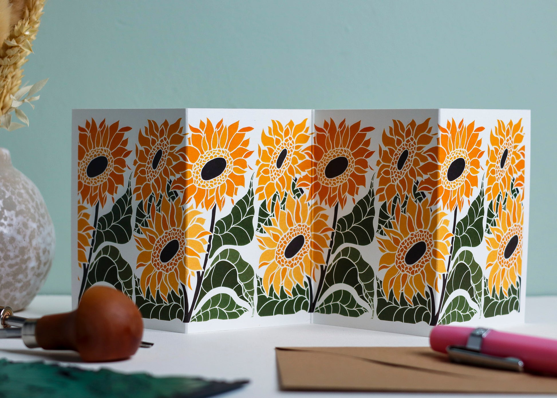 Joy Bloom Sunflower Garland card featuring hand-carved linocut botanical portrait in sunshine yellow. Double-sided concertina greeting card with bold, contemporary cottagecore design on eco-friendly recycled cardstock.