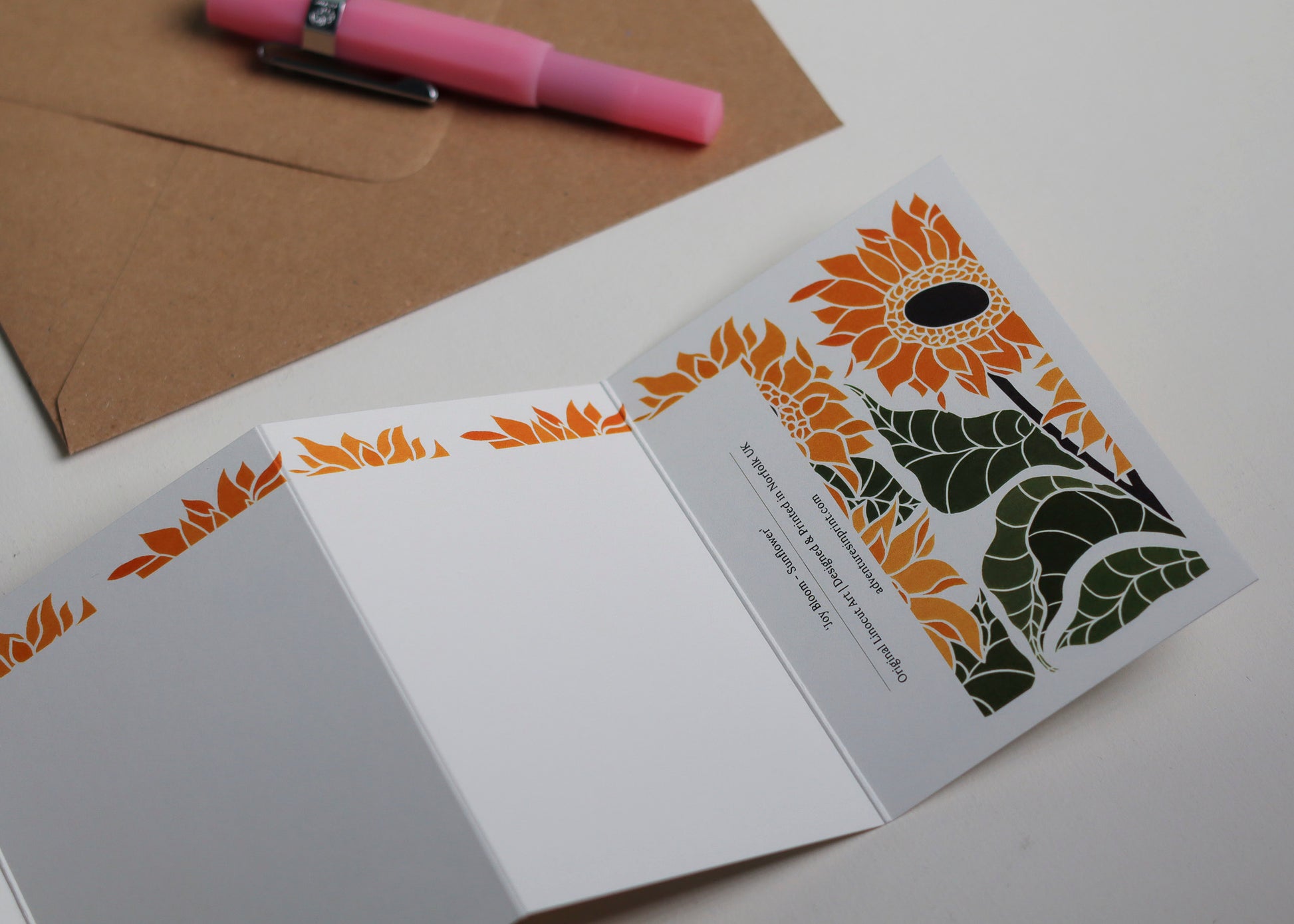 Joy Bloom Sunflower Garland card with C6 kraft envelope. Hand-carved botanical portrait greeting card in sunshine yellows on recycled cardstock, photographed with eco-friendly envelope, ready for posting.