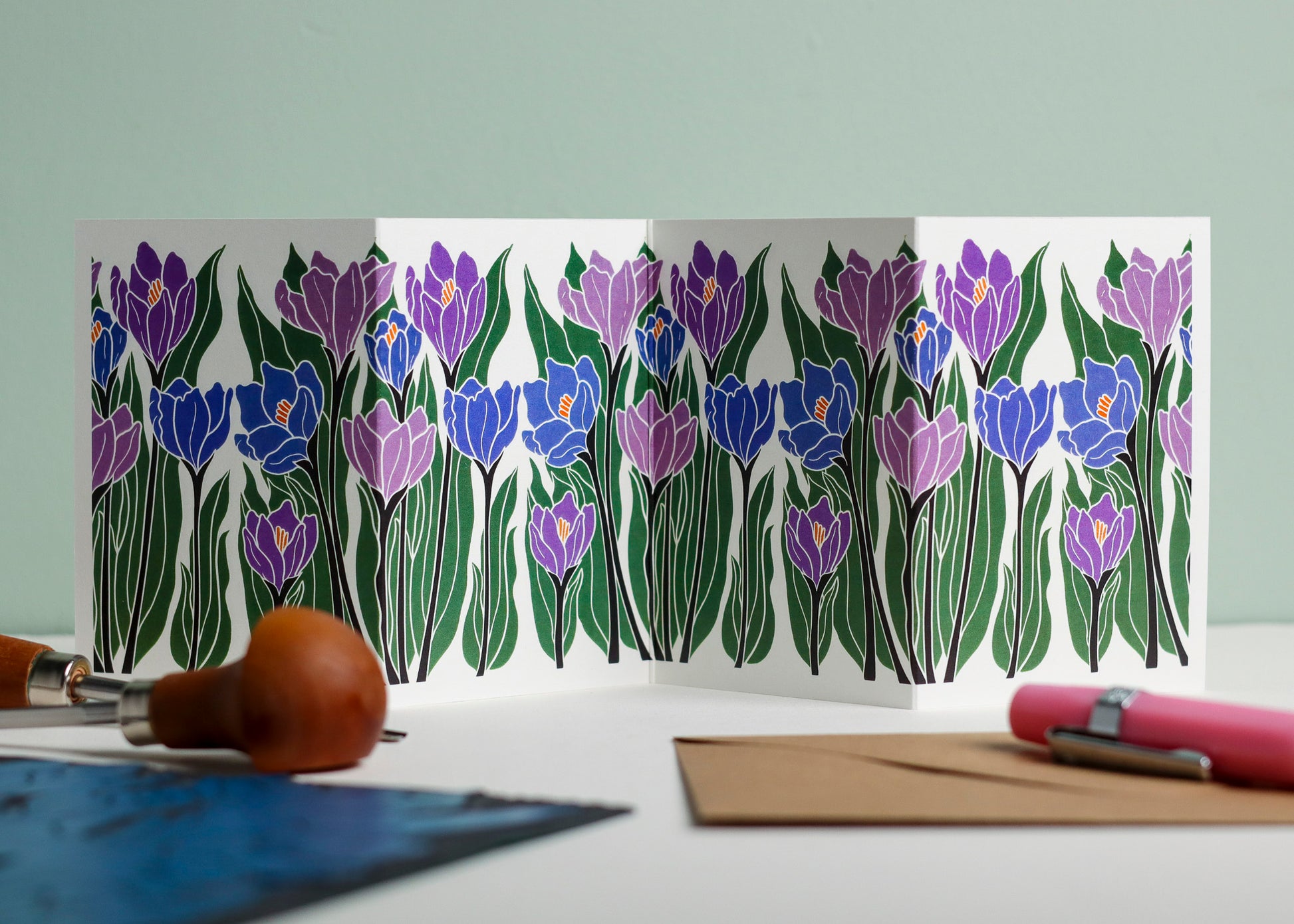 Crocus botanical Garland card shown fully extended (105 x 297mm), displaying complete hand-carved linocut design. Modern cottagecore crocus portrait in purple and blue, perfect for mantlepiece display.