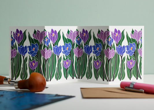 Crocus botanical Garland card shown fully extended (105 x 297mm), displaying complete hand-carved linocut design. Modern cottagecore crocus portrait in purple and blue, perfect for mantlepiece display.