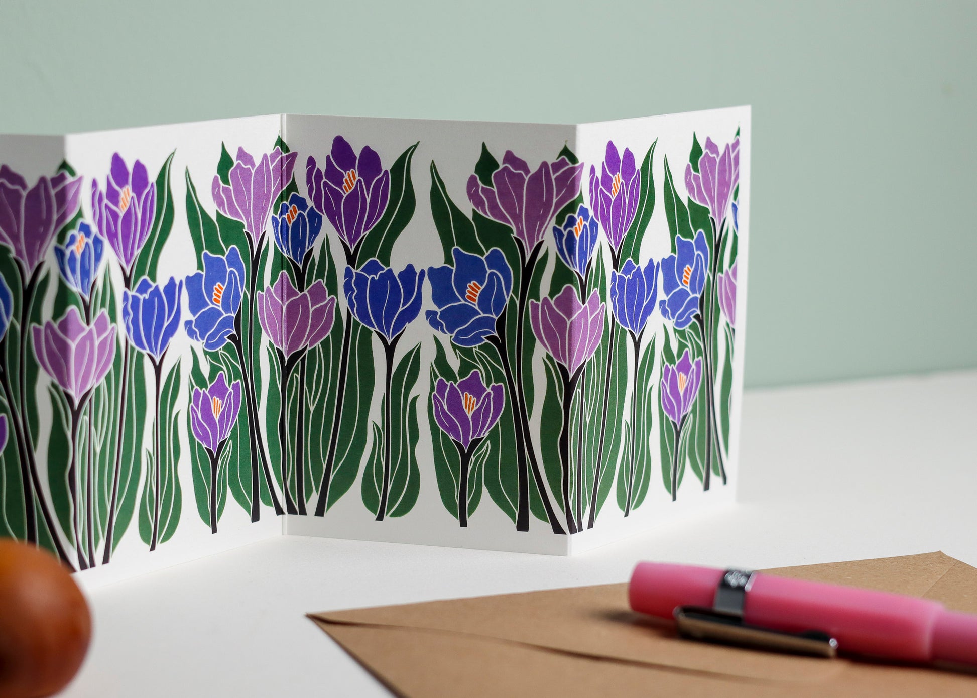 Close-up detail of hand-carved Crocus flower design on Garland card. Bold purple and blue colours and graphic linocut linework showing botanical accuracy and contemporary colour palette.