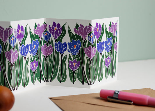 Close-up detail of hand-carved Crocus flower design on Garland card. Bold purple and blue colours and graphic linocut linework showing botanical accuracy and contemporary colour palette.