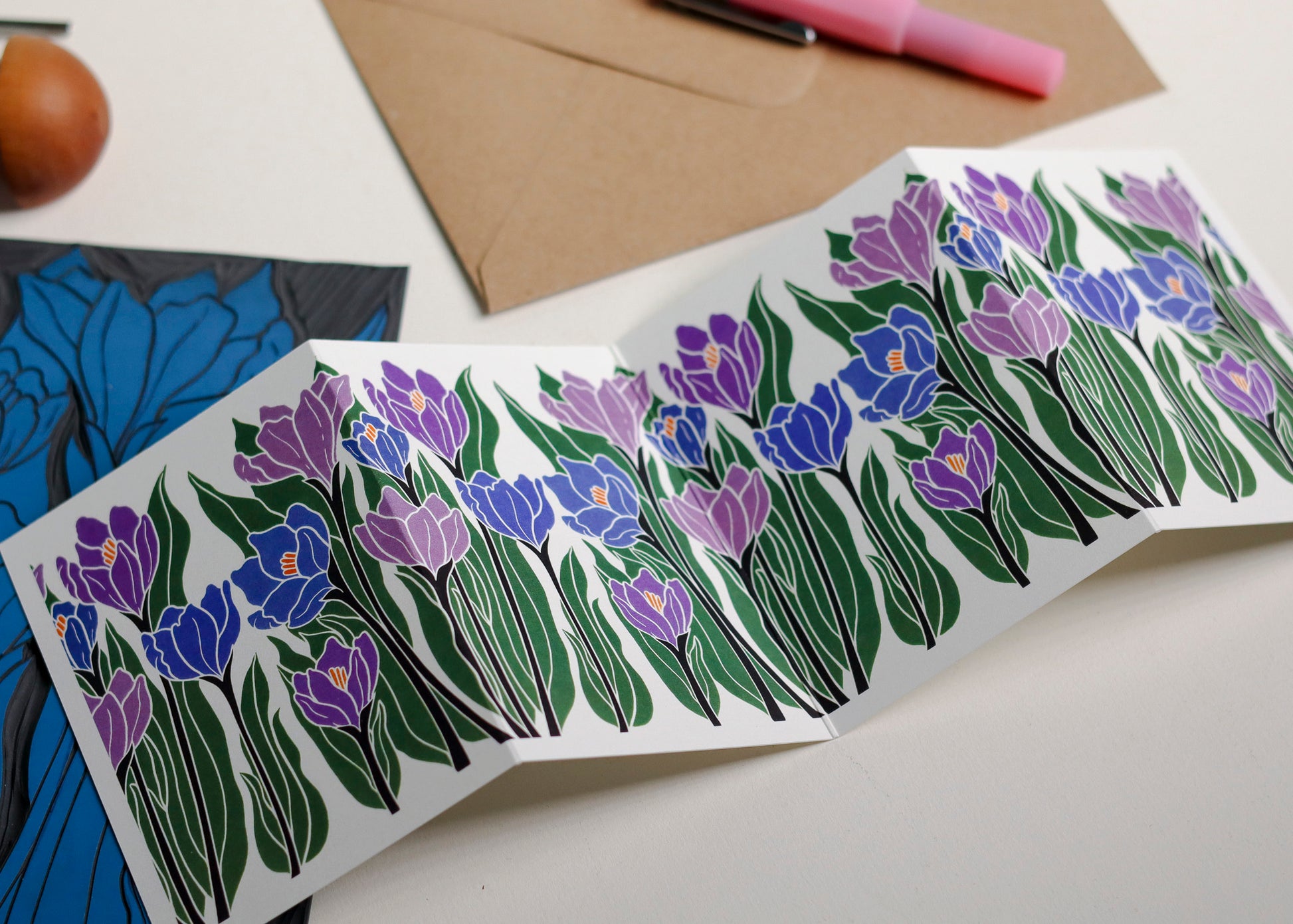 Crocus Garland card featuring hand-carved linocut botanical portrait in purple and blues. Double-sided concertina greeting card with bold, contemporary cottagecore design on eco-friendly recycled cardstock.