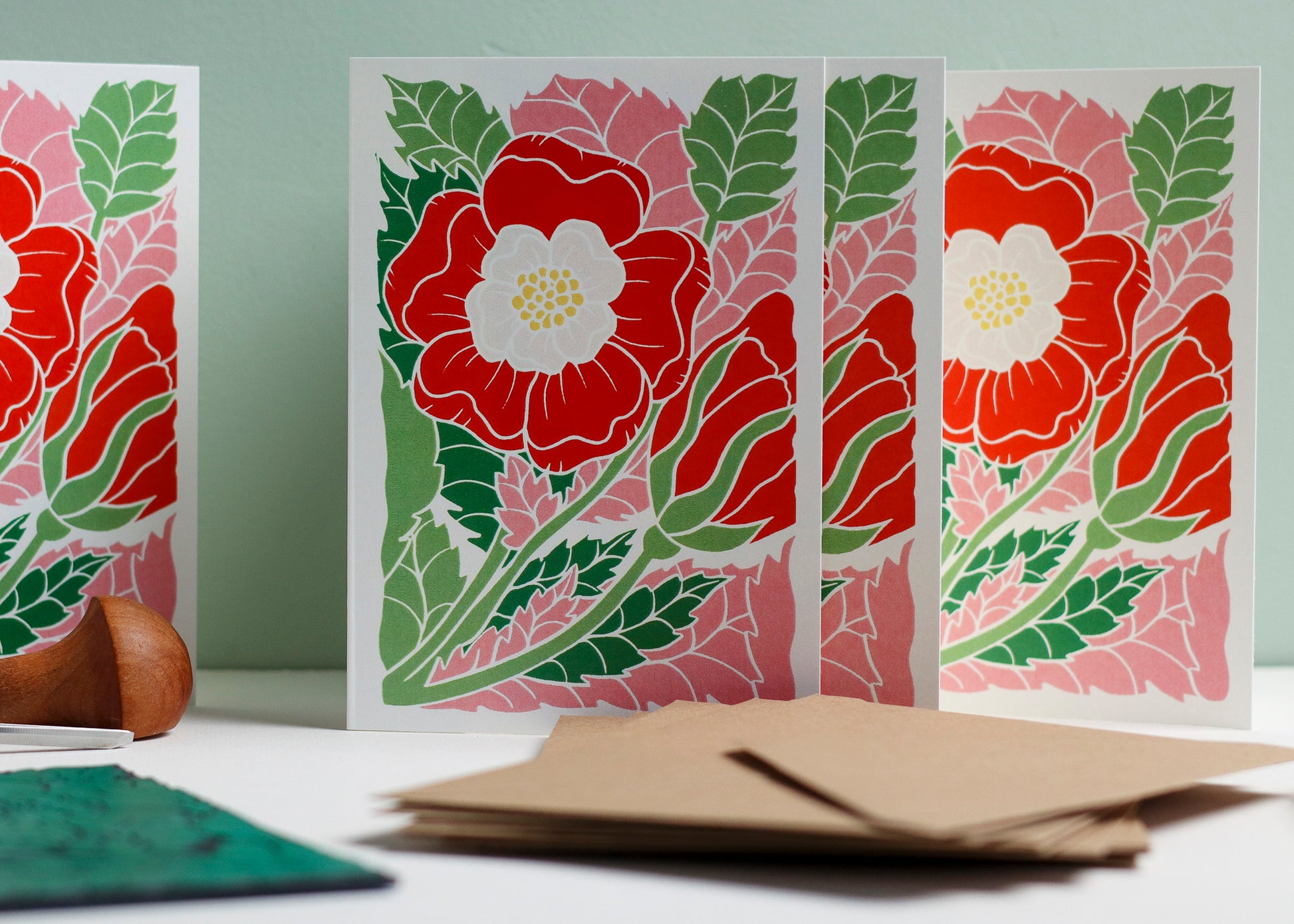 Set of 8 hand carved botanical notecards featuring the English Tudor rose. A6 linocut print greeting cards in eye-catching red and pink, displayed with kraft envelopes. Cottagecore stationery on recycled cardstock.