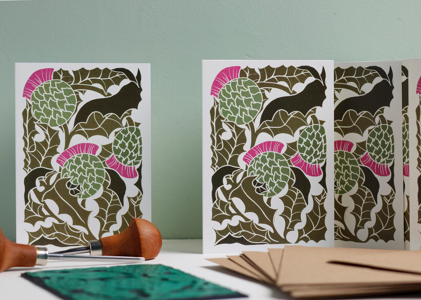 Set of 8 hand-carved botanical notecards featuring Scottish Thistles. A6 linocut print greeting cards in classic thistle green, displayed with kraft envelopes. Cottagecore stationery on recycled cardstock.
