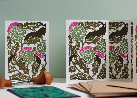 Set of 8 hand-carved botanical notecards featuring Scottish Thistles. A6 linocut print greeting cards in classic thistle green, displayed with kraft envelopes. Cottagecore stationery on recycled cardstock.