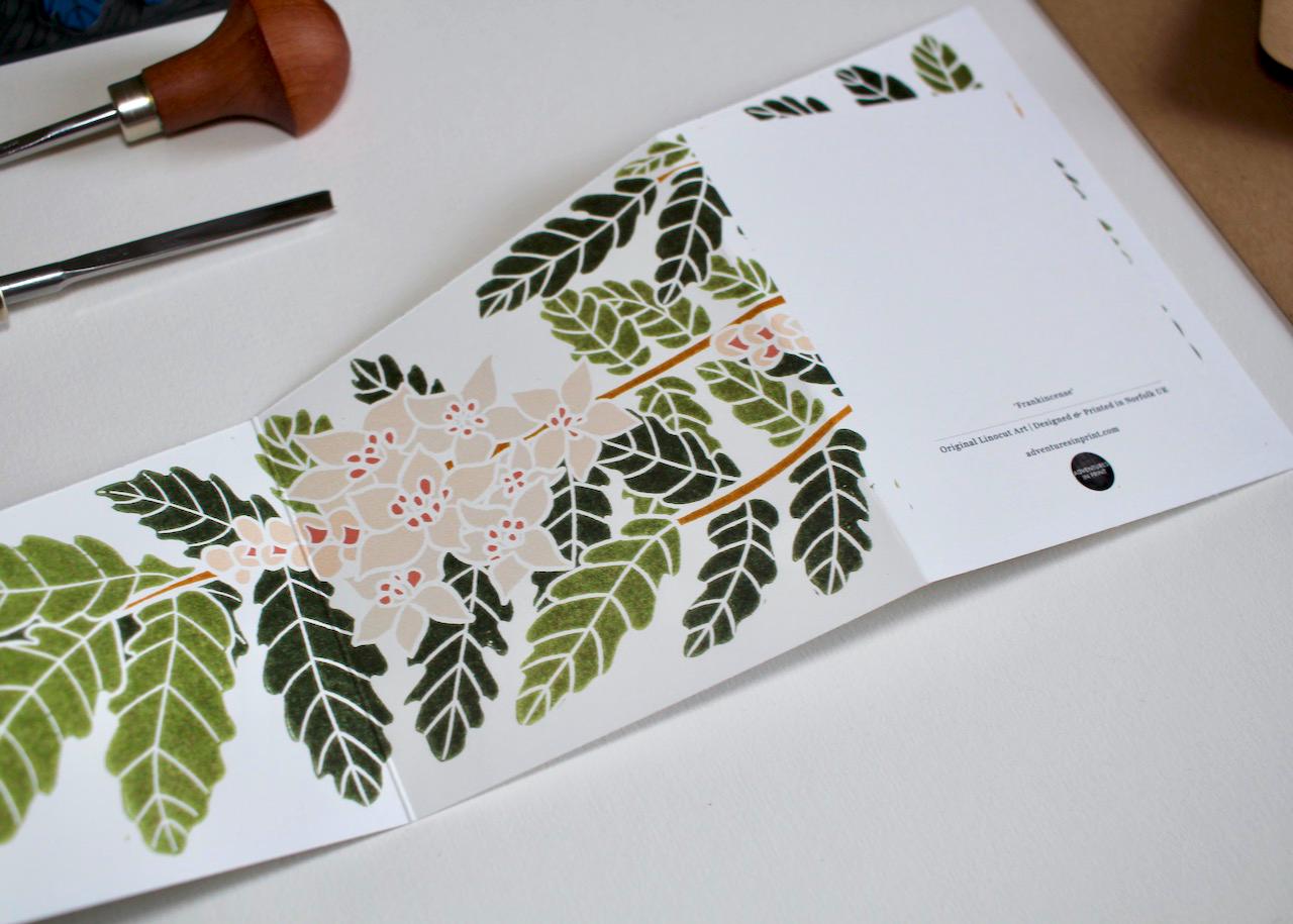 A double sided concertina Christmas card featuring linocut artwork of the frankincense tree and flowers