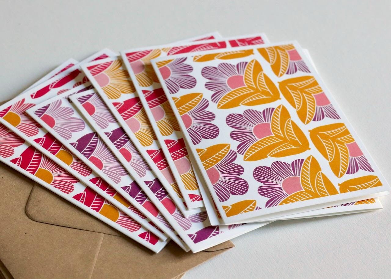 Complete stationery set featuring 8 handmade linocut cards with abstract sunrise-inspired floral pattern, arranged with matching kraft envelopes